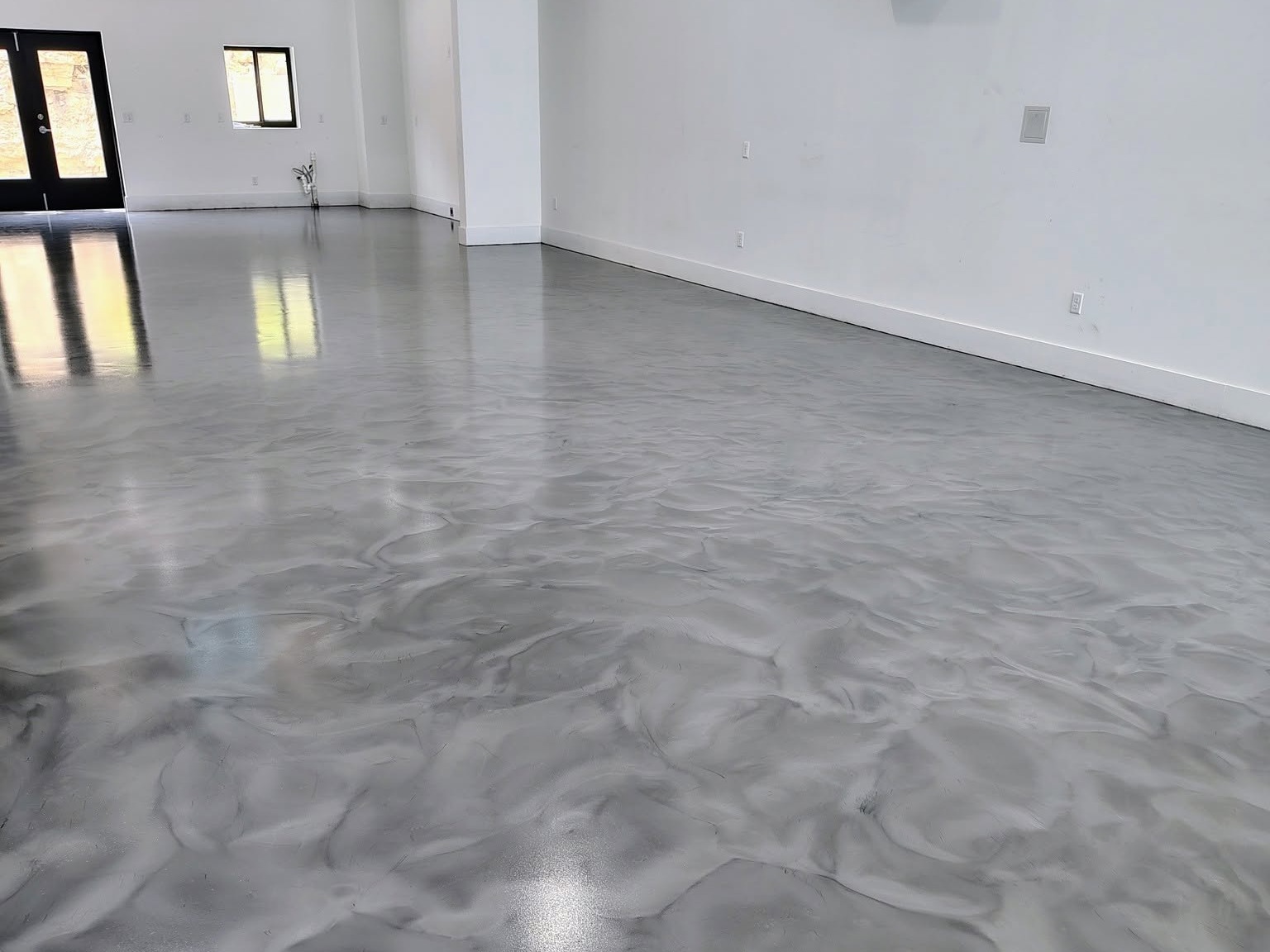 Gray and white metallic epoxy floor with a marbled swirl pattern in a bright open room.