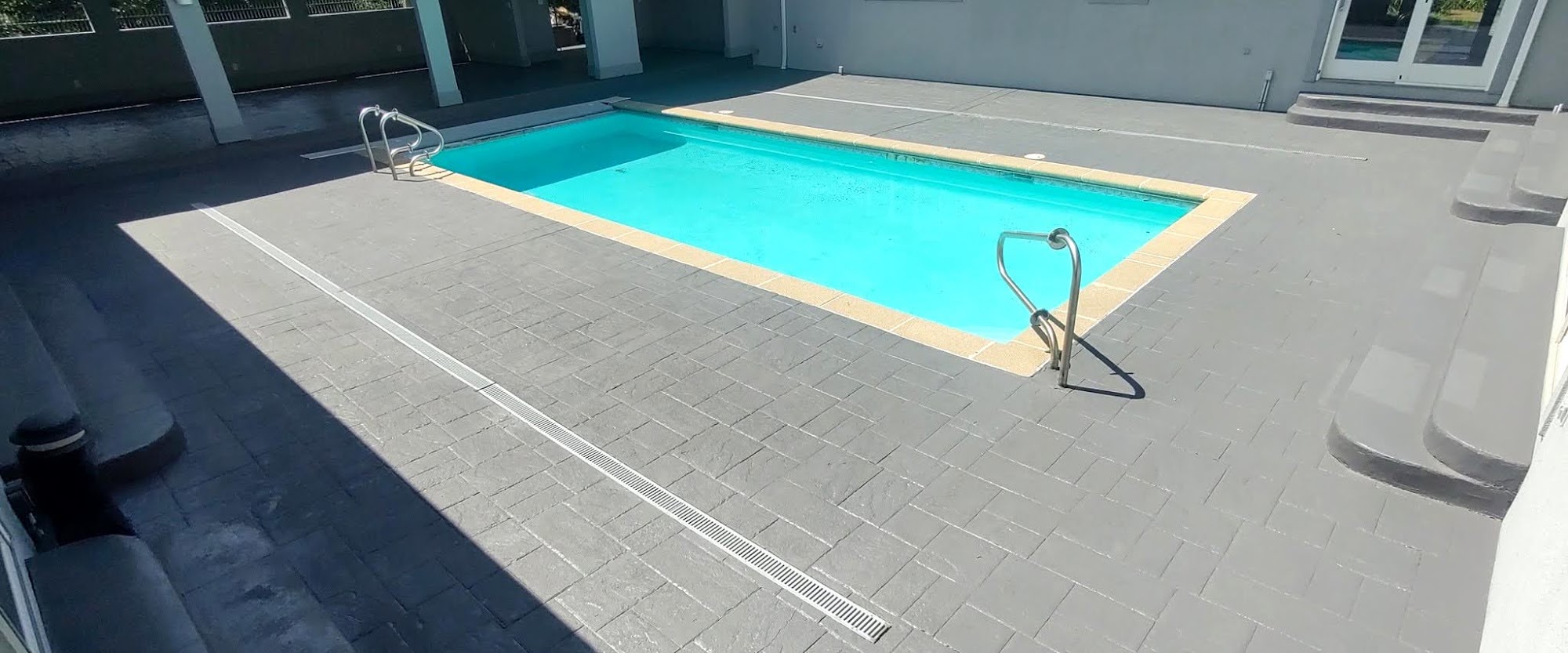 Gray stamped concrete pool deck with a trench drain