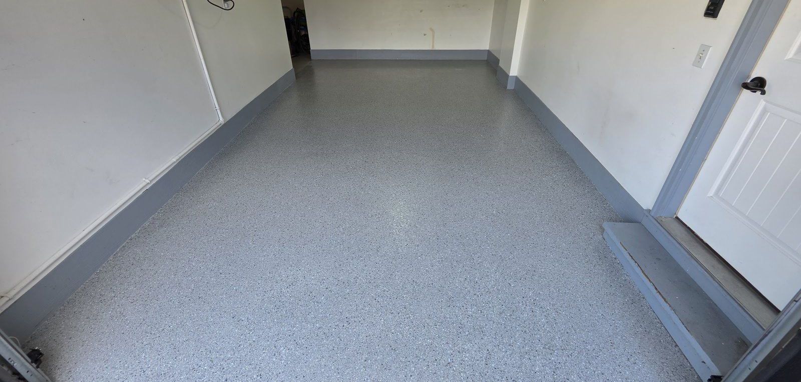 Long garage bay with a gray flake epoxy floor and coated stem walls in Columbia, MO