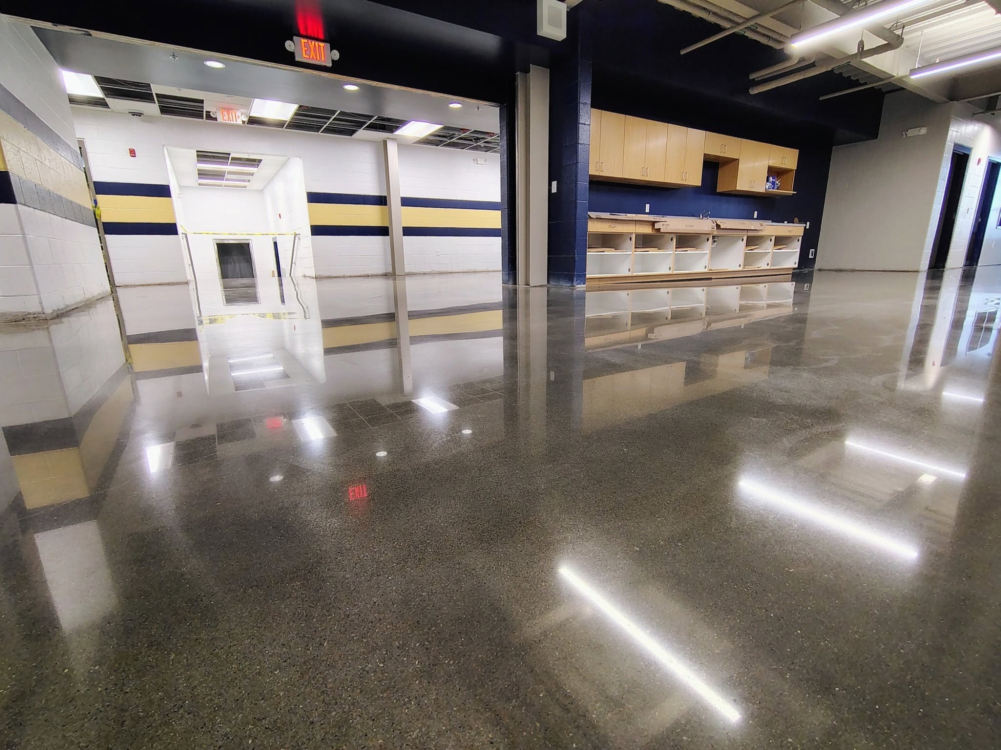 High-gloss polished concrete floor with exposed aggregate in a school commons area.
